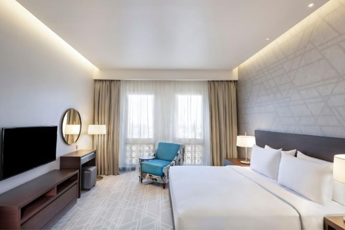 Een hotelkamer met een bed, een televisie, een bureau en een stoel.