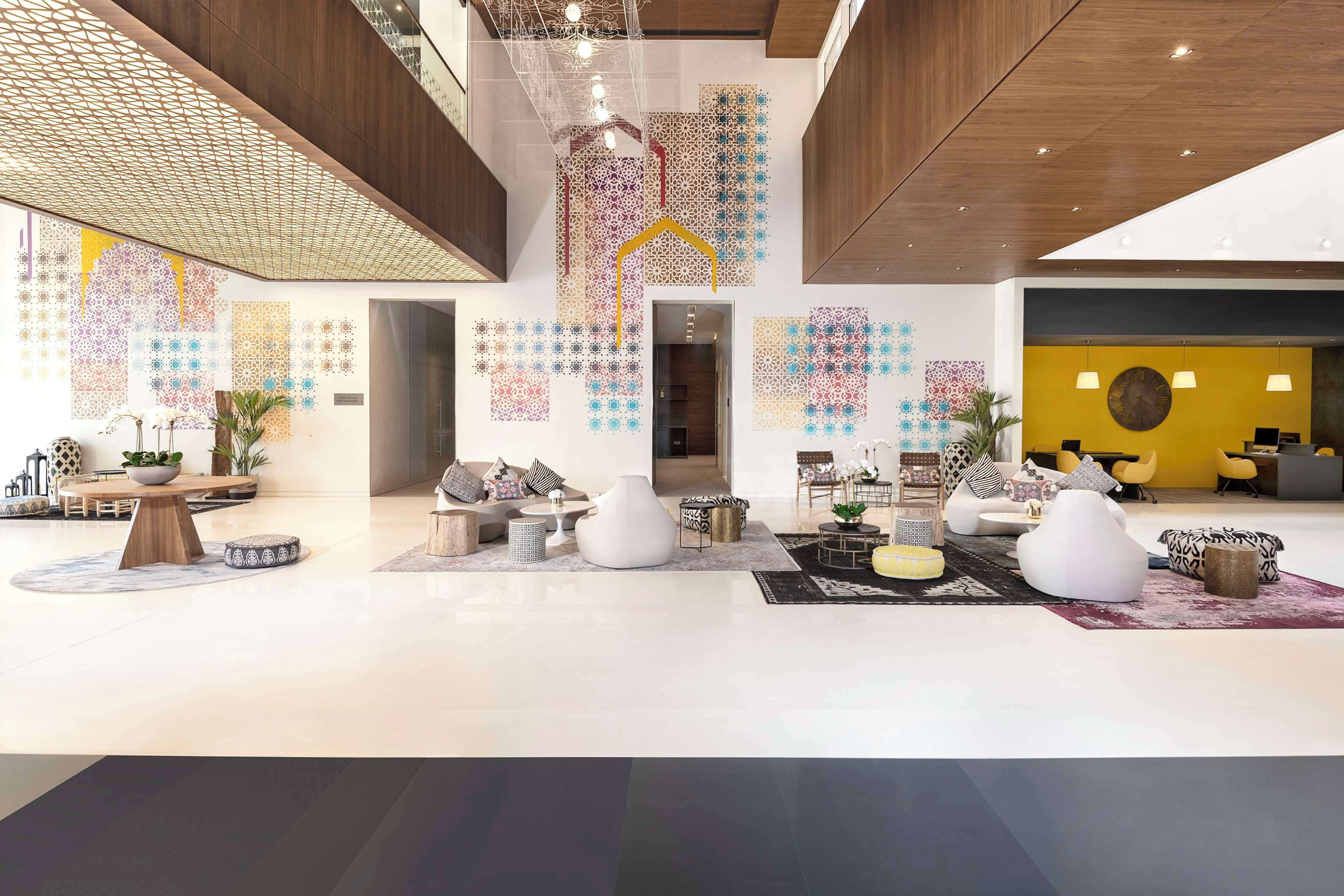 Een ruime lobby met moderne meubels, een receptiebalie en decoratieve muurkunst.