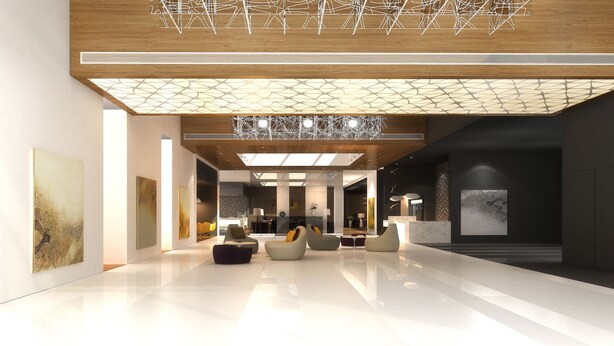 Een ruime lobby met een modern design, met een hoge plafond, een geometrische lamp en een zithoek met banken en stoelen.