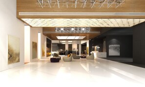 Un hall d’entrée spacieux au design moderne, avec un plafond haut, un luminaire aux formes géométriques et un espace détente comprenant des canapés et des fauteuils.