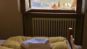 Une chambre avec un lit, une fenêtre donnant sur les montagnes et un radiateur.
