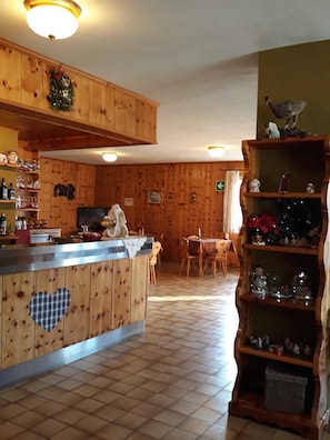 A wooden interior with a kitchen area, including a counter with heart-shaped cutouts, a dining table, and a shelf with figurines. - Hotel Ginepro (Valdisotto)