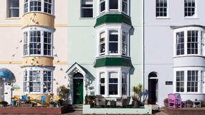 A row of colorful Victorian-style buildings with bay windows and a pub sign. - Channel View Guest House (Weymouth)