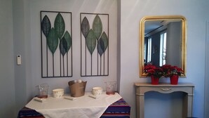 A room with a table set for dining, a mirror above it, and two leaf-patterned wall art pieces. - Hôtel Linxa (Tours)
