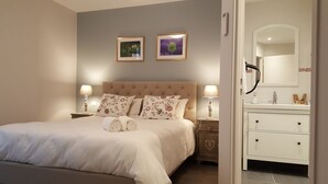 A bedroom with a large bed, two nightstands with lamps, a dresser, and a bathroom visible through an open door. - Hôtel Linxa (Tours)