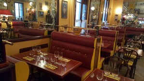 A restaurant interior with red booths, tables with wine glasses, and a mirror reflecting the room. - Hôtel Linxa (Tours)