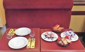 A dining table set with plates, cutlery, and a basket of bread and croissants. - Hôtel Linxa (Tours)