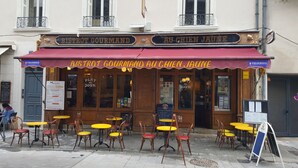 A restaurant with outdoor seating, a red awning, and a sign reading "BISTROT GOURMAND AU CHIEN JAUNE". - Hôtel Linxa (Tours)