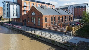 A riverside building with a brick facade, large windows, and outdoor seating. - Premier Inn Gloucester - Quayside (Gloucester)