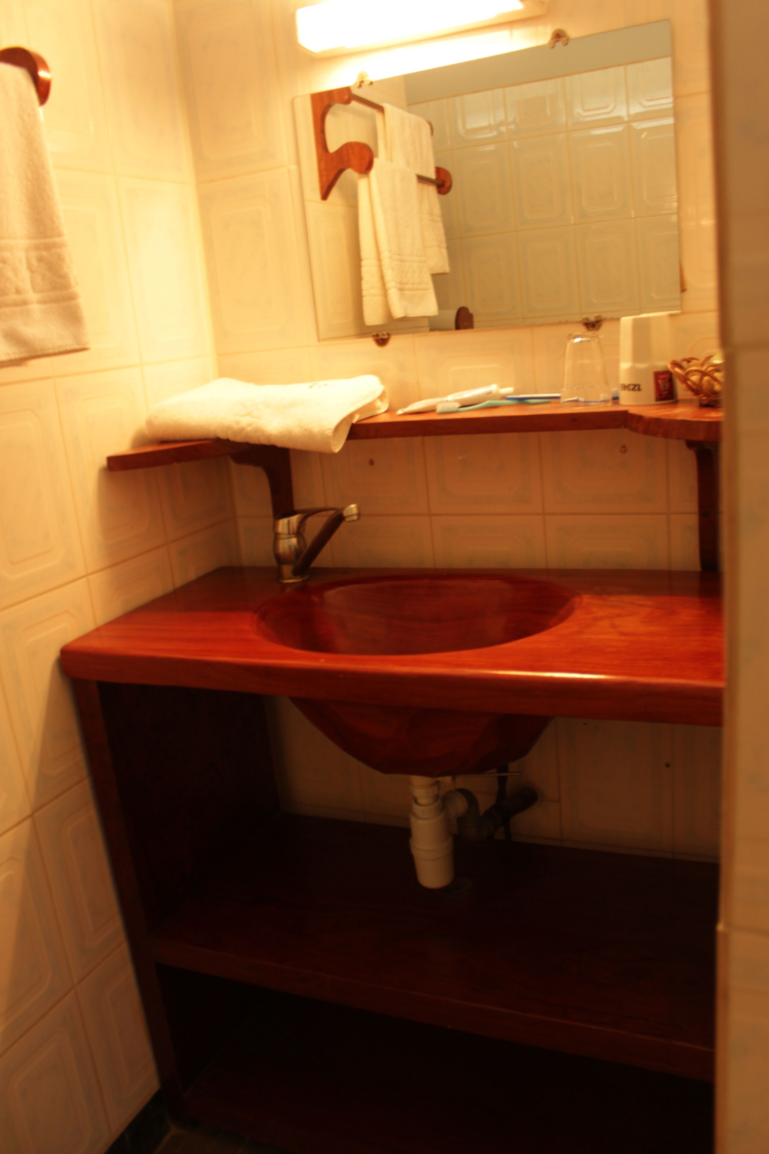 A bathroom with a wooden sink, a mirror, and a towel hanging on the wall.