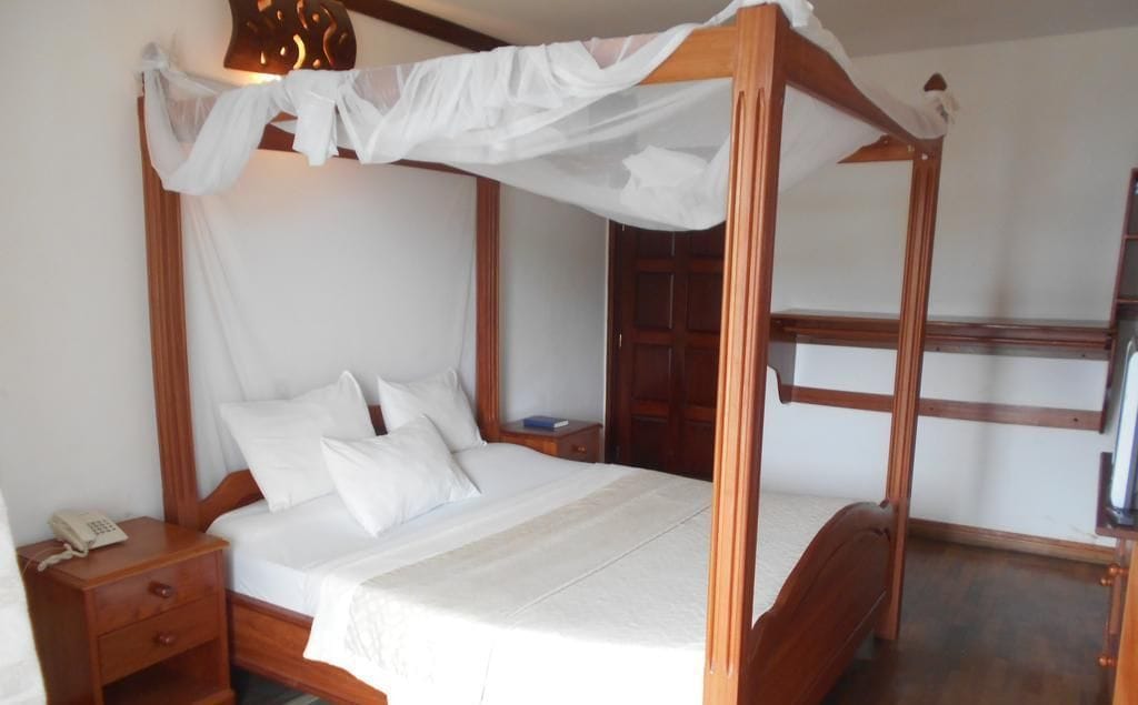 Un lit à baldaquin avec du linge de lit blanc et un cadre en bois.