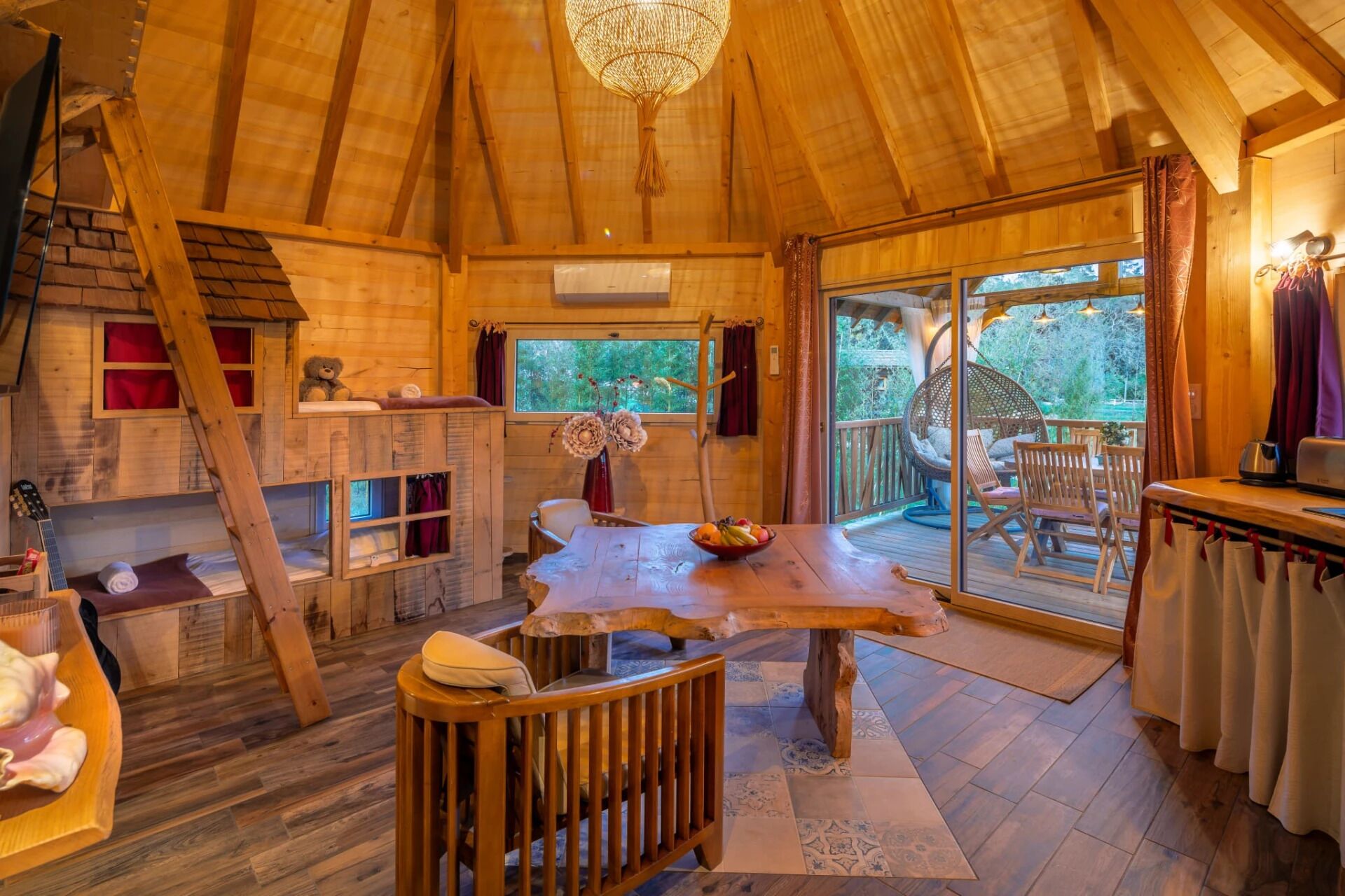 L’intérieur chaleureux d’un chalet en bois comprend un coin repas, un lit en mezzanine et une grande fenêtre donnant sur l’extérieur.