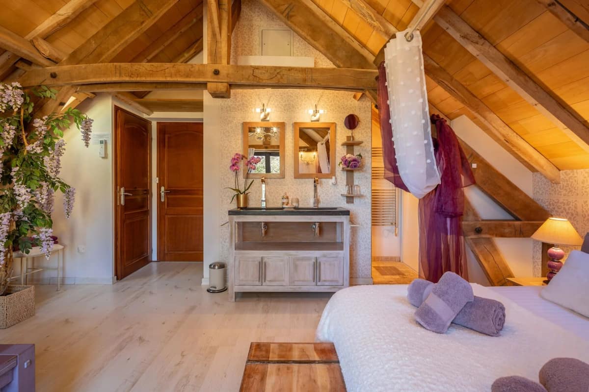 Slaapkamer met houten plafond, een bed met handdoeken, een kaptafel met spiegel en een hangende douchegordijn.