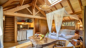 L’intérieur chaleureux d’un chalet avec une table à manger en bois, un lit à baldaquin et un coin cuisine.