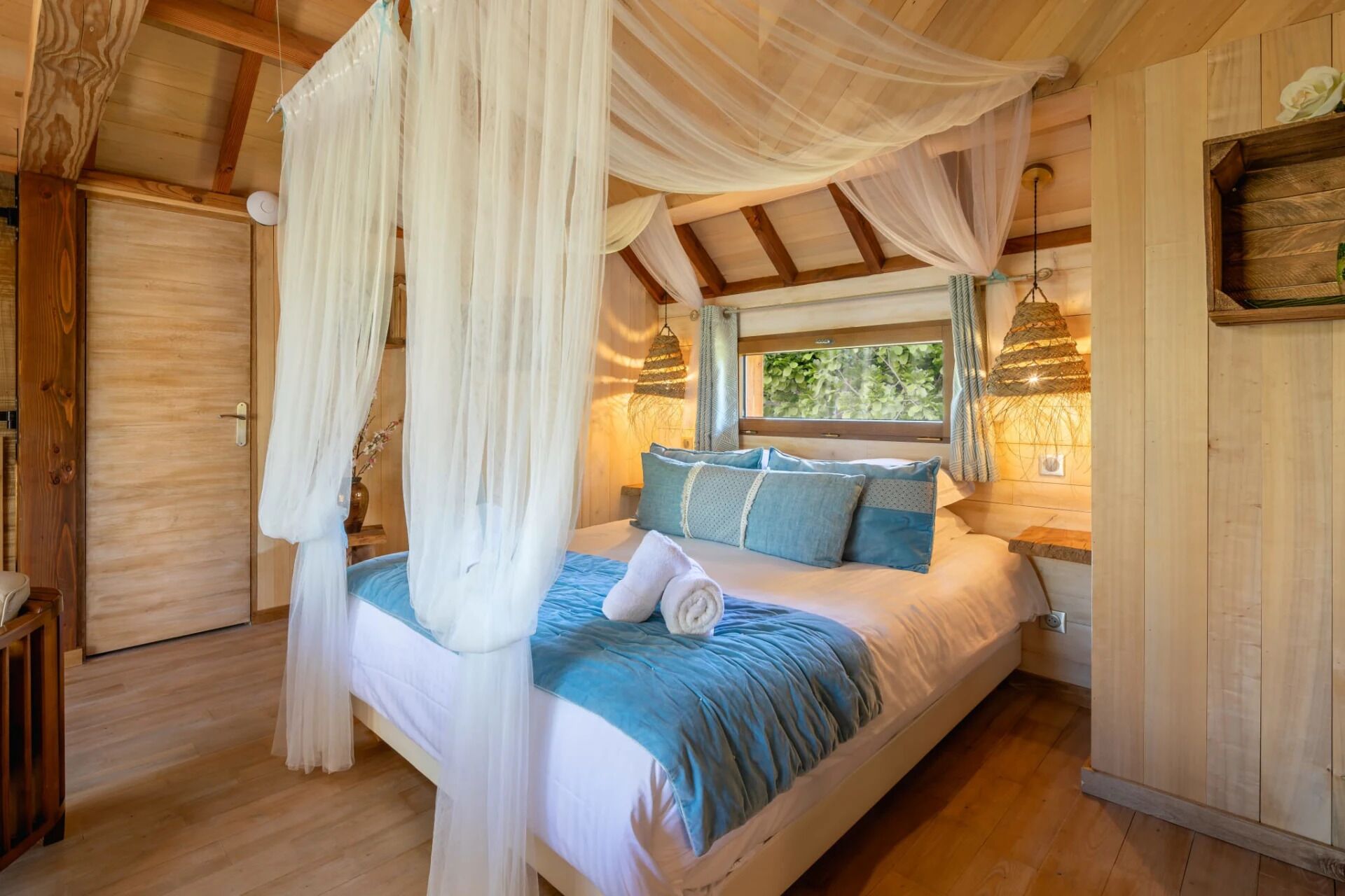 A bedroom with a canopy bed, wooden walls, and a window with a view of greenery.