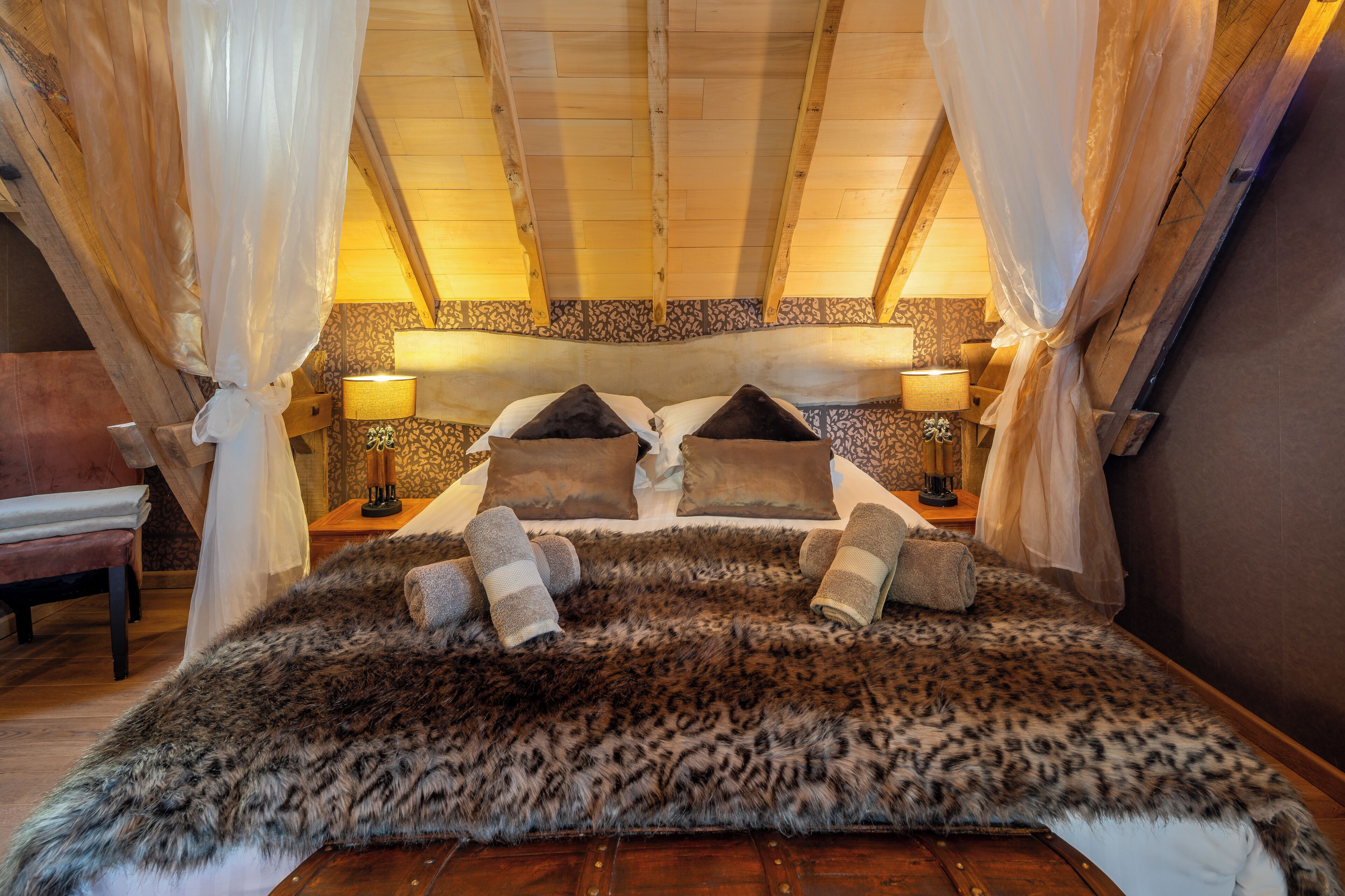 A cozy bedroom with a fur-covered bed, wooden headboard, and two bedside lamps.