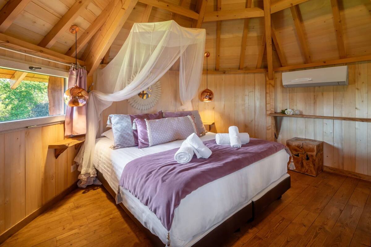 Een houten kamer met een bed, een raam en een plafondventilator.