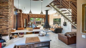 Une cuisine moderne dotée d’un îlot central, d’un coin repas avec une grande table et d’un espace salon confortable avec un canapé et un fauteuil.