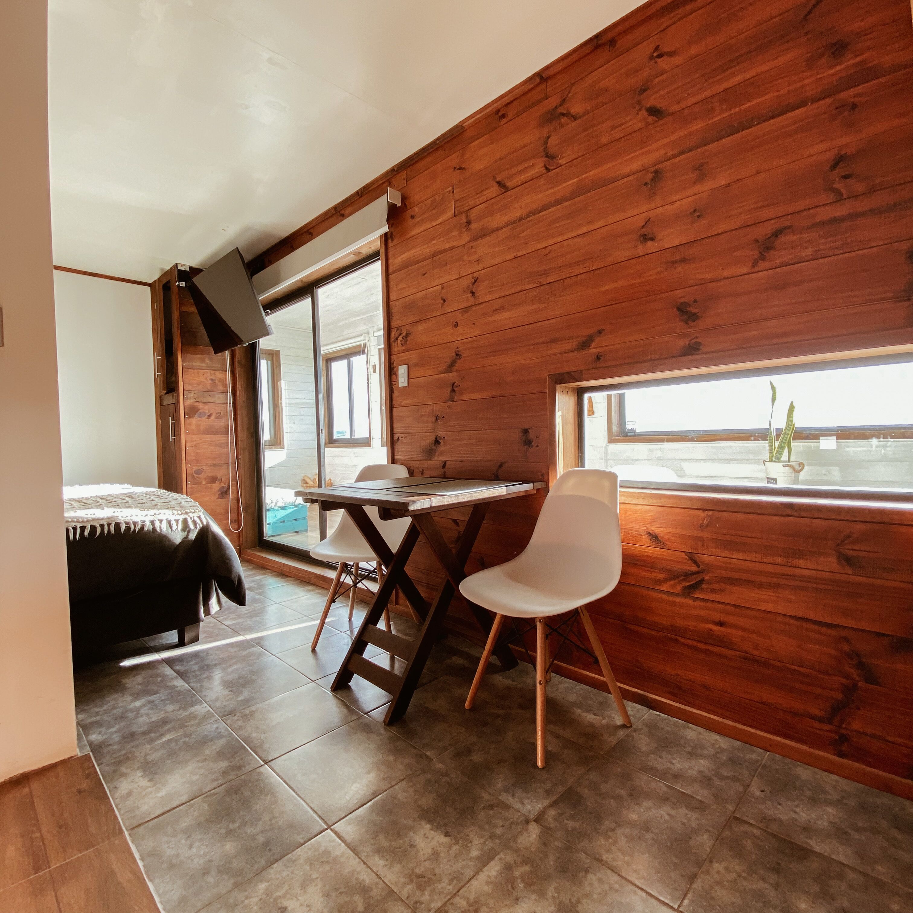 Une pièce aux murs en bois, avec un lit, un bureau et une chaise.