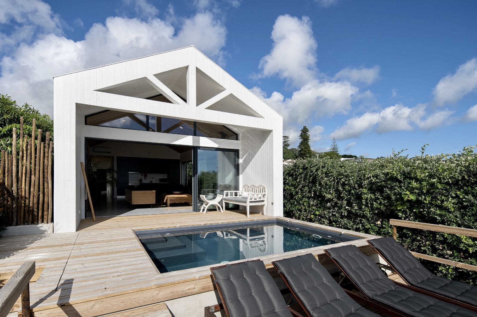 Une maison moderne avec une piscine, un espace salon extérieur et une vue sur le ciel.
