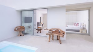 Ein modernes Interieur mit einer Glastür, die zu einem Schlafzimmer, einem Poolbereich und Holzmöbeln führt.