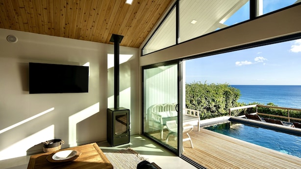 Ein modernes Wohnzimmer mit einem großen Fenster mit Blick auf einen Pool und das Meer.