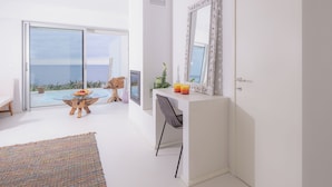 Ein modernes Zimmer mit Glastür zum Balkon, einem weißen Schreibtisch mit Stuhl und einem großen Spiegel.