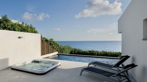 Eine Dachterrasse mit Whirlpool, Liegestühlen und Meerblick.