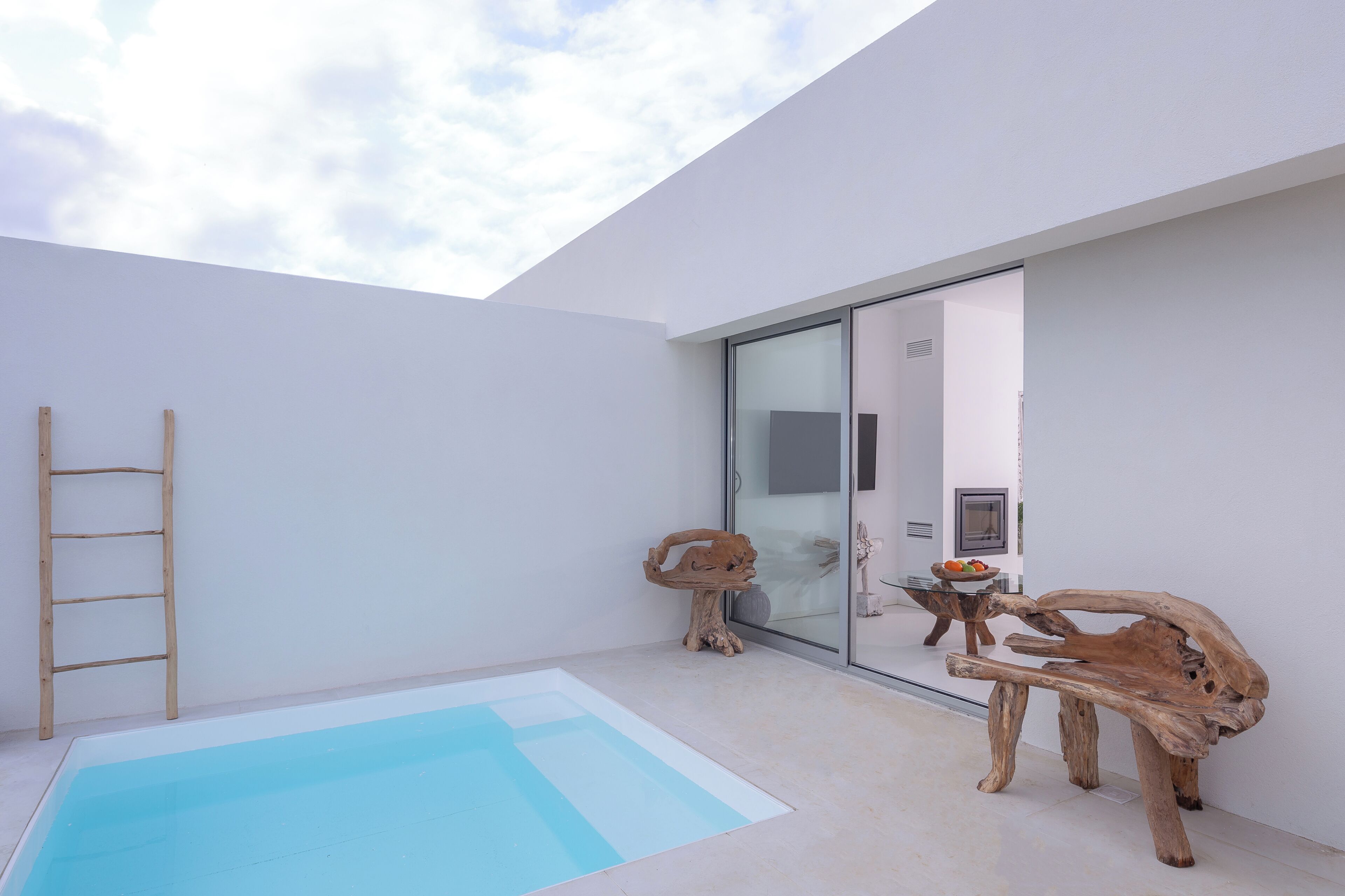 A modern interior with a pool, wooden furniture, and a glass door leading to another room.