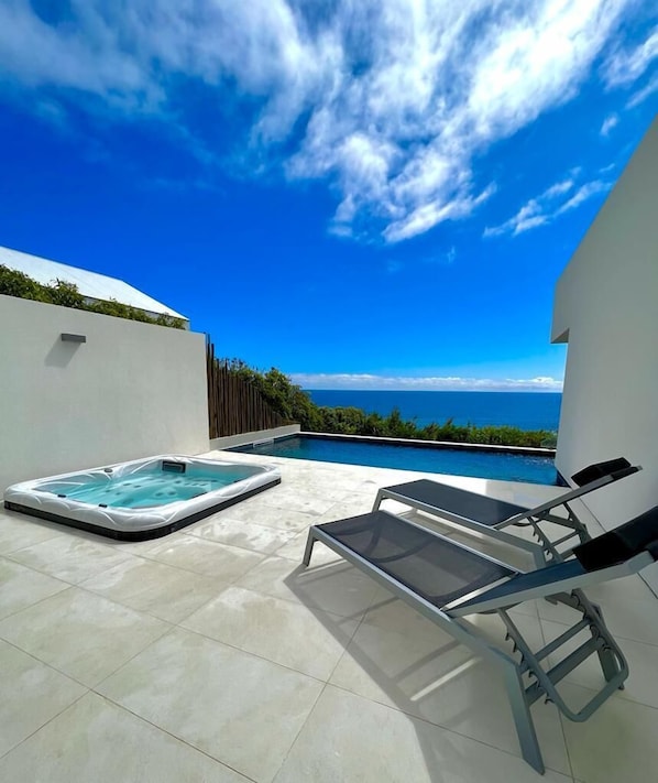 A rooftop pool area with a hot tub and lounge chairs, overlooking a clear blue sky and ocean. - Sul Villas & Spa (Lagoa)