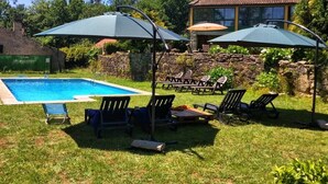 A backyard with a swimming pool, lounge chairs, and umbrellas. - Casa da Urcela (Ponteareas)