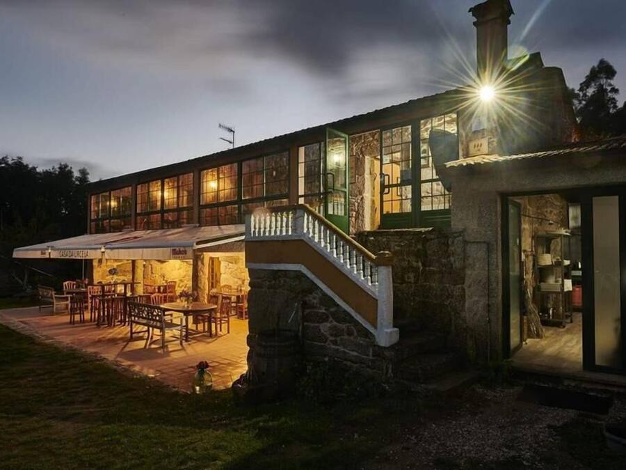 Edificio de piedra con una escalera que conduce a un patio cubierto con mobiliario exterior.