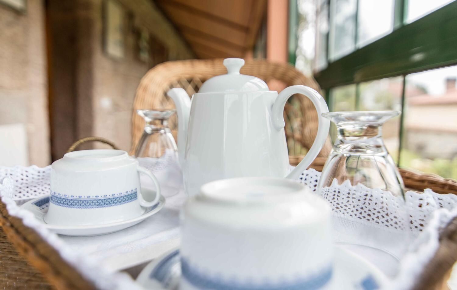 A tray with a teapot, a cup, and a sugar bowl on a wicker table.