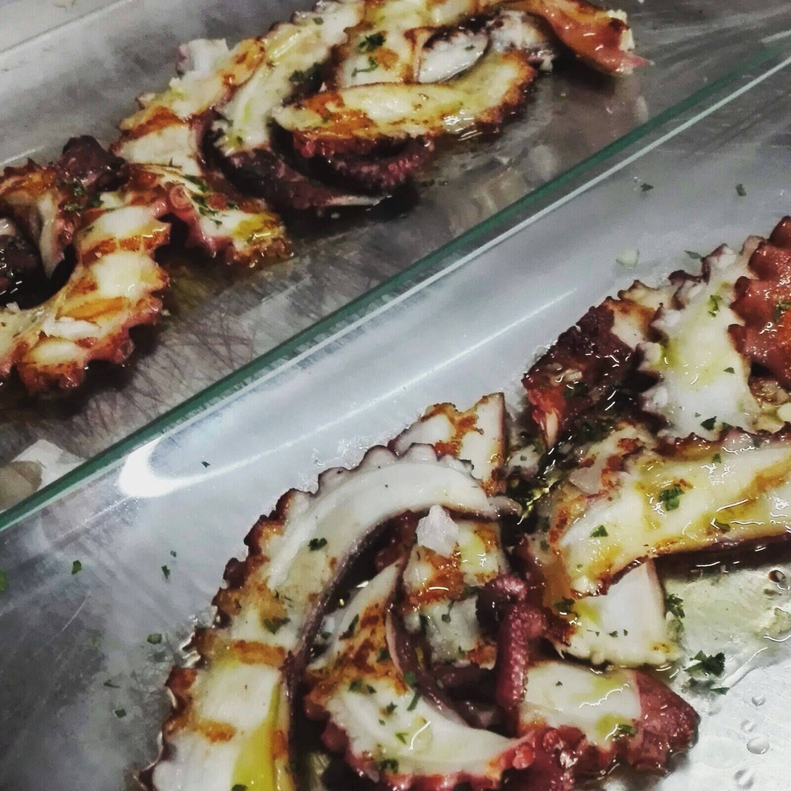 A glass display case with sliced octopus, seasoned with herbs and melted cheese.