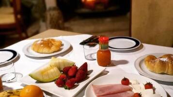 Una mesa lista para el desayuno, con platos de comida, una botella de salsa y una chimenea al fondo.