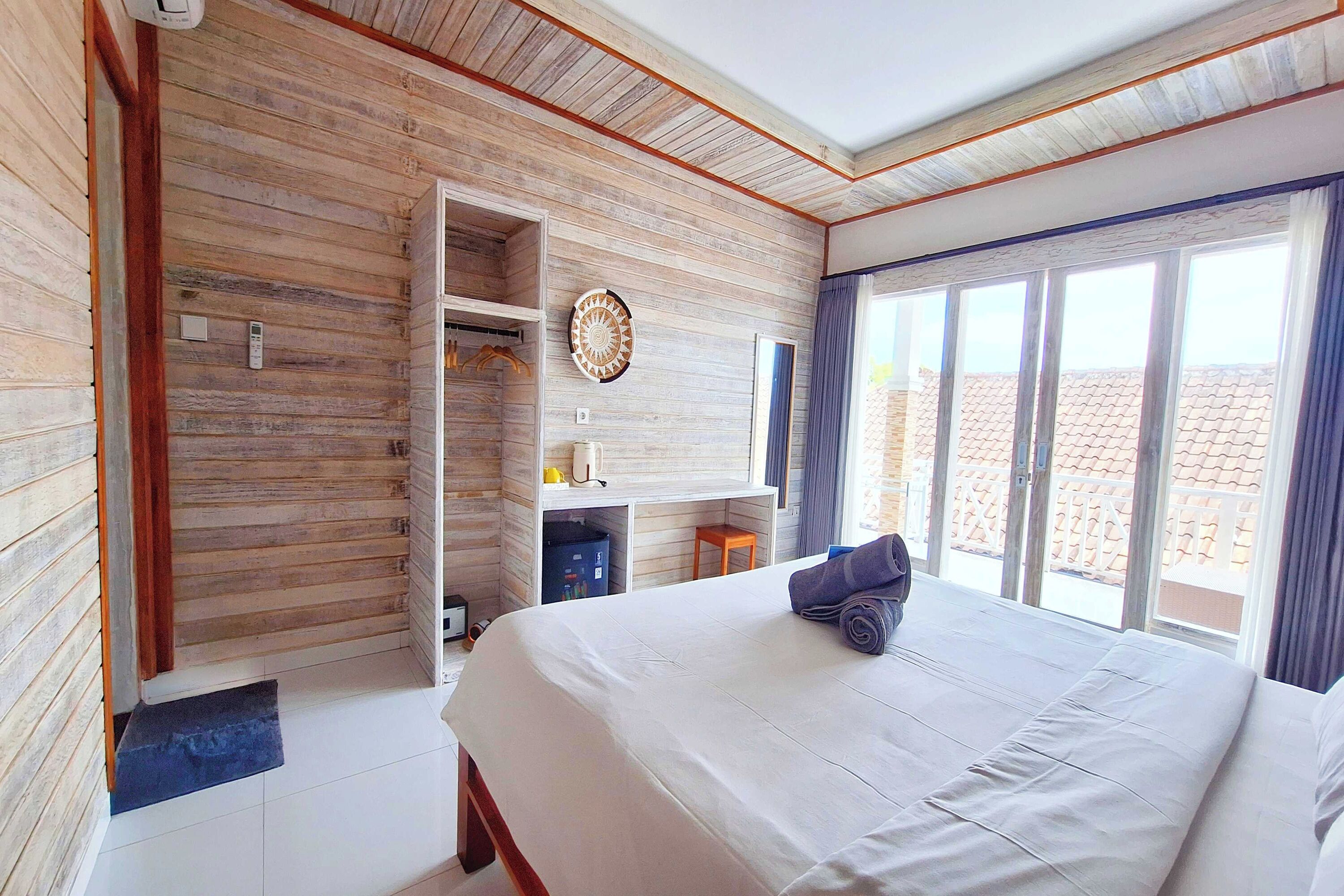 Une chambre avec un grand lit, un mur en bois, un bureau et une fenêtre donnant sur un beau paysage.