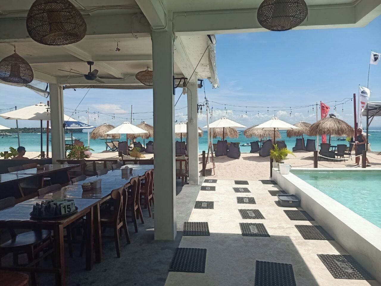 Een restaurant aan het strand met terras, een zwembad en parasols.