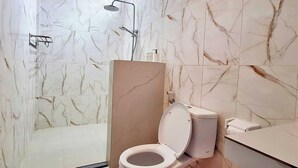 A modern bathroom with a toilet, shower, and marble walls. - The Beach Huts Lembongan (Lembongan Island)
