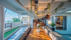 Un intérieur moderne avec une longue table à manger, des sièges et une vue sur l’extérieur.
