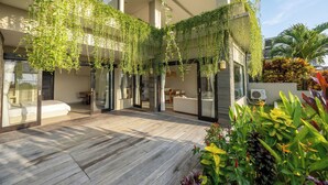 Un bâtiment moderne doté d’une terrasse en bois, de plantes d’intérieur et d’un espace salon.
