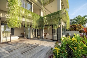 Een modern gebouw met een houten terras, kamerplanten en een zithoek.