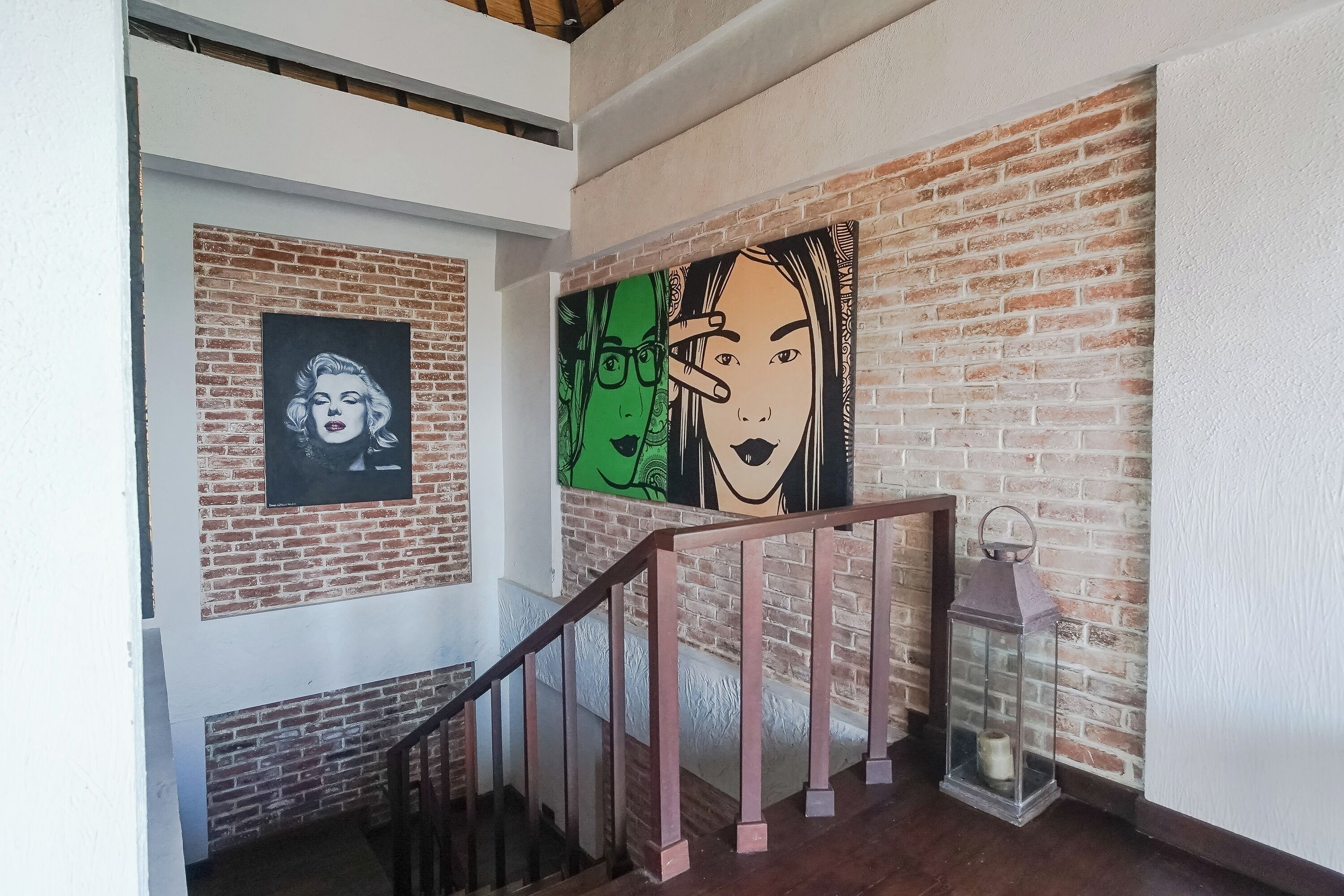 Een trap met een bakstenen muur en twee kunstwerken in lijsten.