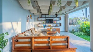 Un salon moderne avec un canapé en bois, un téléviseur et des plantes suspendues.