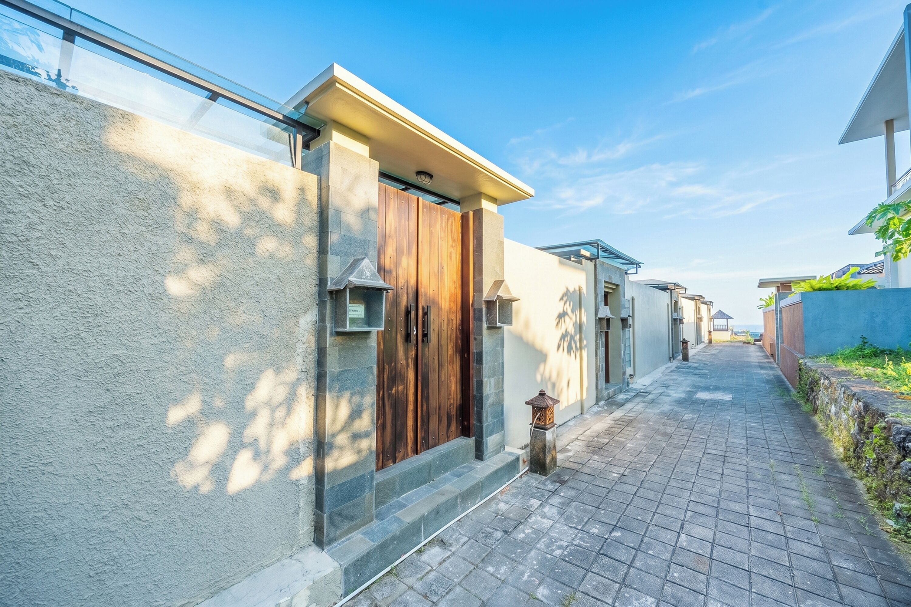A narrow paved pathway leading to a building with a wooden door and a small lantern.