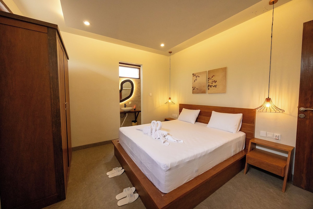 Ein Hotelzimmer mit einem hölzernen Bett, einem Nachttisch, einer Wandleuchte und einem Spiegel.