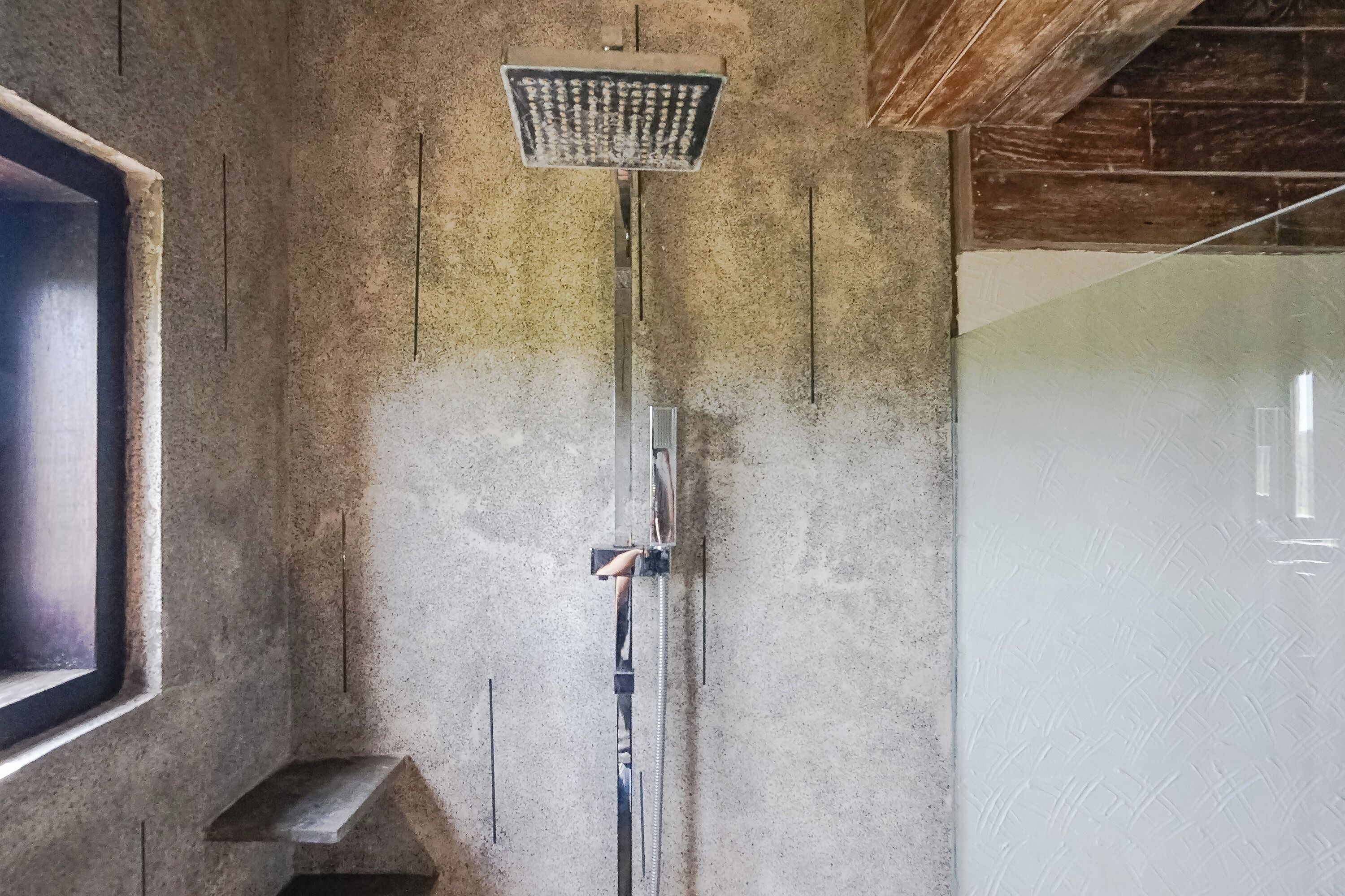 A shower with a handheld showerhead mounted on a wall.