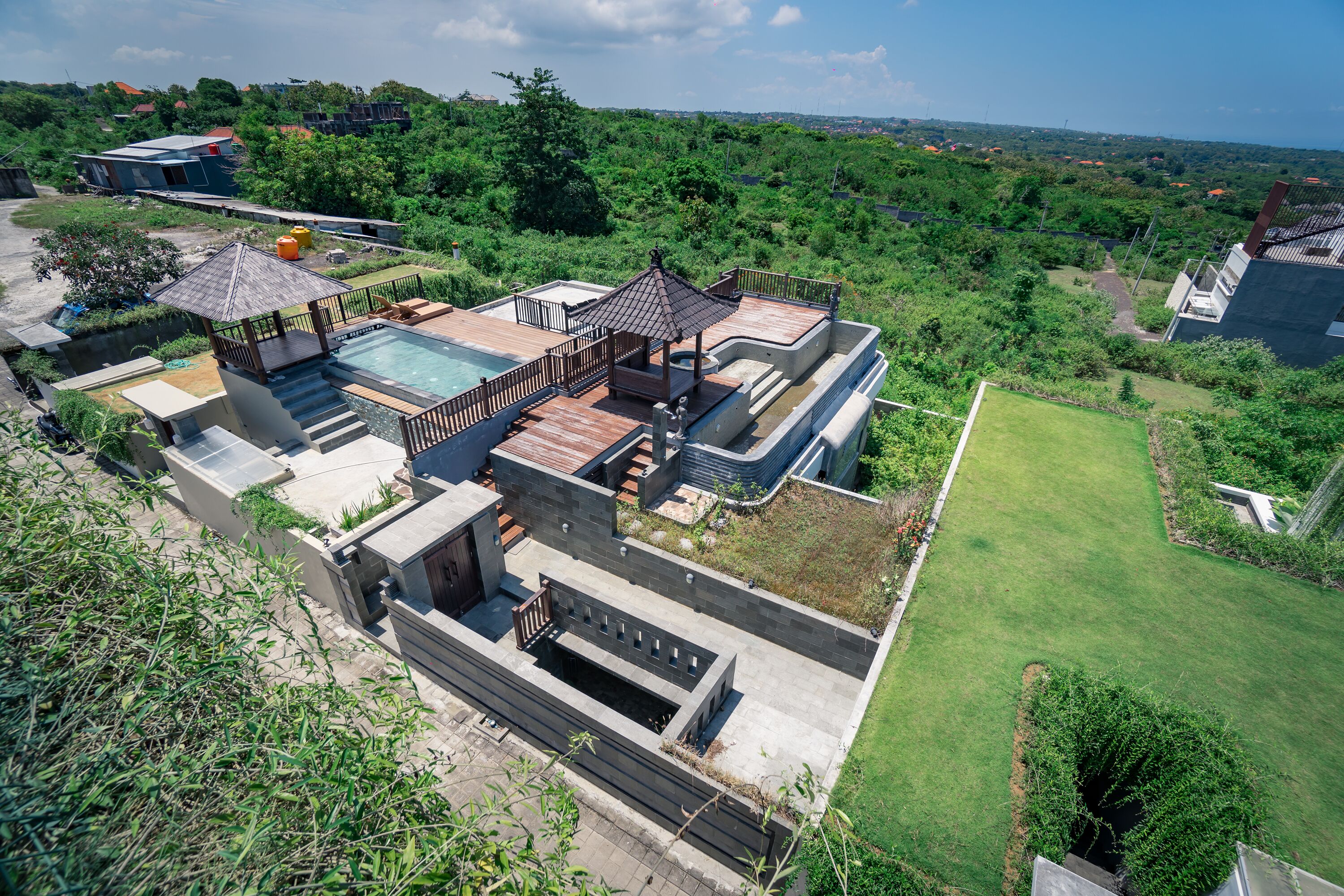 Ein modernes Haus mit Swimmingpool, einer überdachten Terrasse und einem üppigen Garten.