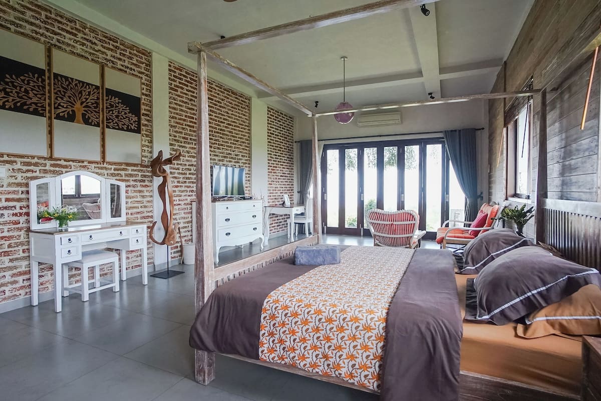 Ein Schlafzimmer mit einem großen Bett, einem Schreibtisch, einem Sessel und einem Kleiderschrank.