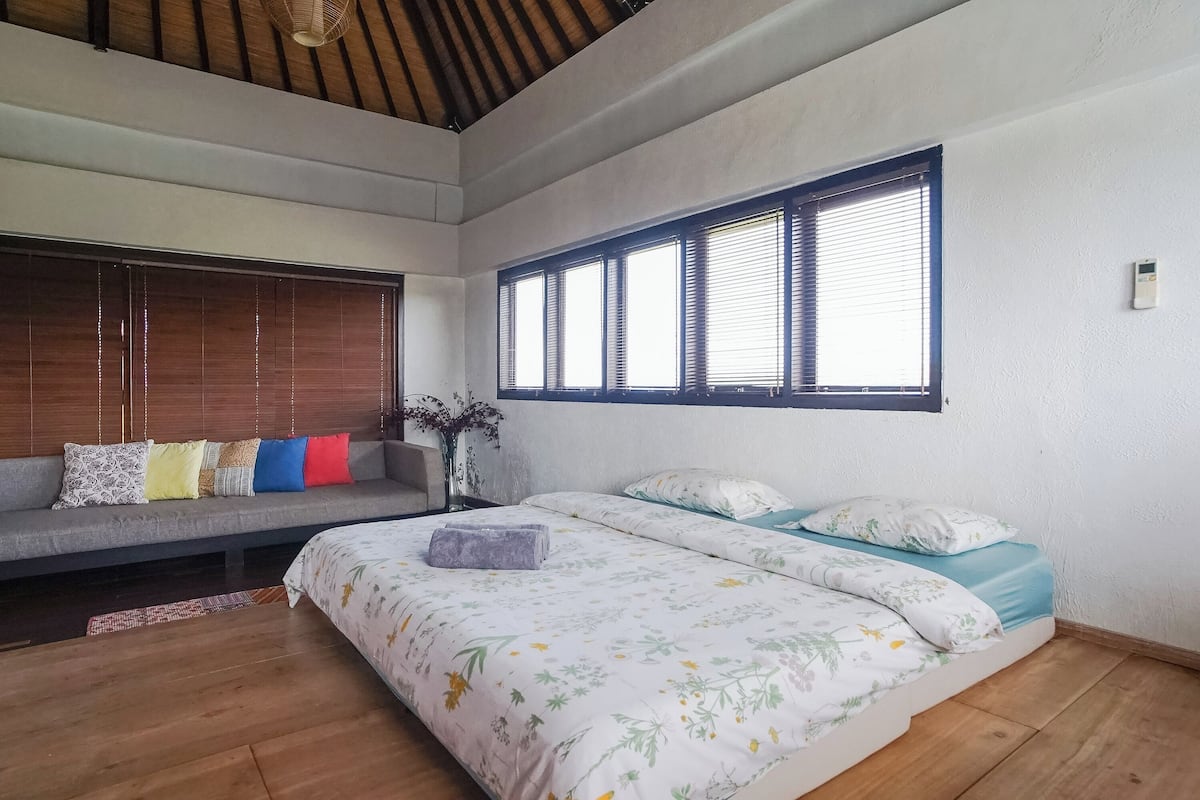 Ein Schlafzimmer mit einem Bett, einem Sofa und einem Fenster mit Jalousien.