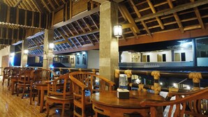 Restaurante com mobiliário de madeira e teto alto com vigas aparentes.